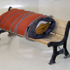 Nul n'a le droit qu'à ce qui suffit, 2009 Empiètements de banc public, planches de coffrage, tiges et barres métalliques, brique, sac de couchage, matelas, chaîne marine, cadenas, 70 x 200 x 50 cm Avec le soutient de l'atelier DEEV (Direction de l'Ecologie et des Espaces Verts), Marseille, 14ème